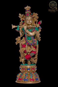 an ornate gold statue with colorful decorations on it's face and arms, sitting in front of a black background