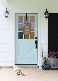 two chickens are standing in front of a blue door and black shutters on a white house