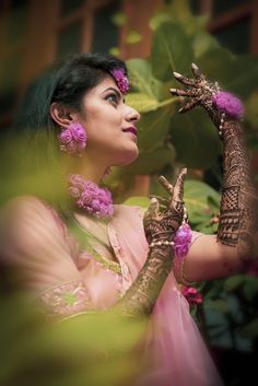 a woman with henna and flowers on her hands is looking up into the sky