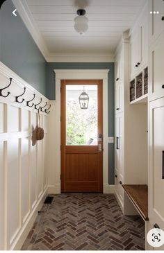 a hallway with white cabinets and a wooden door in the center, next to a window