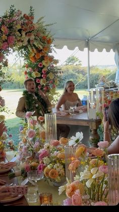 a group of people sitting around a table covered in flowers