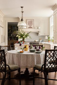 a kitchen table with two chairs and a white table cloth on it in front of an oven