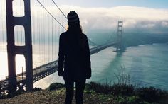 a woman standing on top of a hill next to the golden gate bridge in san francisco