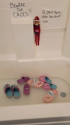 several pairs of shoes are in the bathtub next to a sign that says beware of the crocs