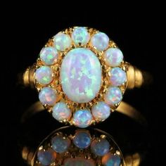 an opalite and diamond ring on a black surface with reflection in the middle