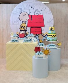 a table topped with cakes and cupcakes covered in frosting next to a wall