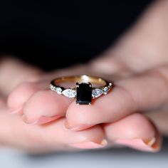 a woman's hand holding an engagement ring with two diamonds on it and a black diamond in the middle