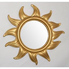 a gold sun shaped mirror on a white wall