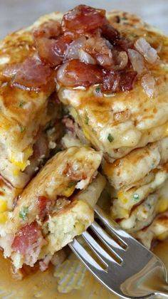 stack of pancakes with bacon and cheese on yellow plate next to fork, closeup