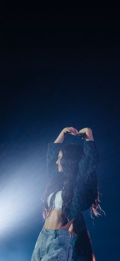 a woman standing in the dark with her hands on her head