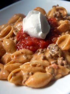 a white plate topped with pasta and meat covered in sauce, cheese and sour cream