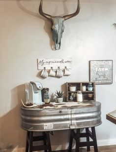 a metal table topped with lots of stuff next to a wall mounted cow skull on the wall