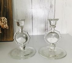 two glass candlesticks sitting on top of a table