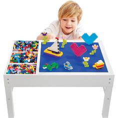 a little boy playing with legos on a table that is made out of plastic