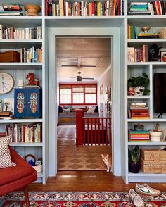 a living room filled with lots of books on top of white shelving unit units