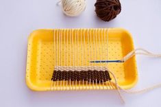 a yellow tray with two skeins of yarn on it and a blue knitting needle