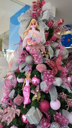 a pink and silver christmas tree decorated with barbie dolls