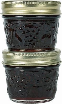 three jars filled with jam sitting side by side on top of each other in metal lids