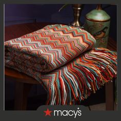 two blankets on a table next to a vase with flowers in it and the words macy's written below