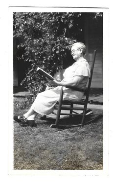 an old woman sitting in a rocking chair reading a book