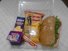 a lunch box with a sandwich, chips, and other snacks in it on a table