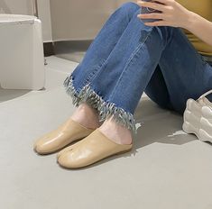 a woman is sitting on the floor with her legs crossed and wearing beige slippers