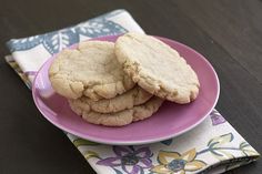 two cookies on a pink plate next to a napkin