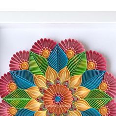 a colorful paper plate with leaves and flowers on it's side, in the shape of a flower