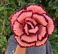 a close up of a person holding a flower in front of a bush and bushes