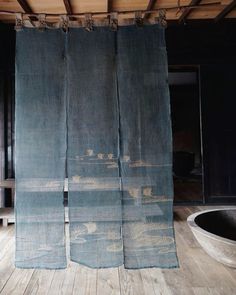 two blue curtains hanging from the side of a wooden floor next to a bathtub