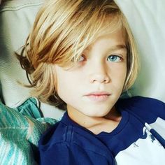 a close up of a child laying on a bed with his head turned to the side