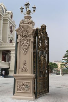 an ornately decorated gate stands in front of a building with two lamps on top