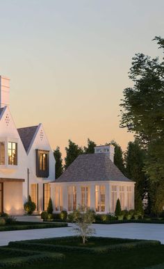 a large white house with lots of windows and bushes in front of it at dusk