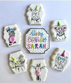 decorated cookies are arranged in the shape of animals and birthday hats with words on them