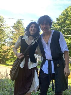 two people dressed in pirate costumes posing for a photo together with trees in the background