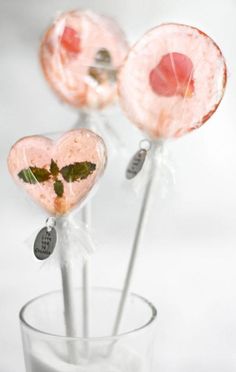 two heart shaped lollipops sitting in a glass filled with milk and mint