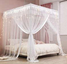 a white canopy bed with sheer curtains and fairy lights on the ceiling, in a pink bedroom