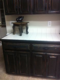 an empty kitchen with wooden cabinets and white counter tops in front of a black vase