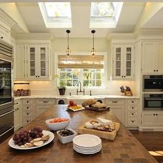 a kitchen filled with lots of white cabinets and counter top covered in food on plates