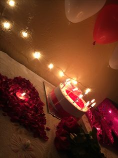 a birthday cake sitting on top of a table next to some balloons and flowers with candles