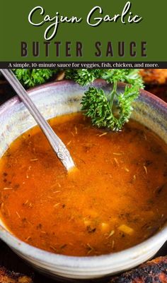 a bowl of butter sauce with a spoon in it and some parsley on the side