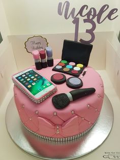 a pink birthday cake with makeup and cell phone on top