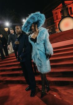 a woman in a blue fur coat standing next to a man