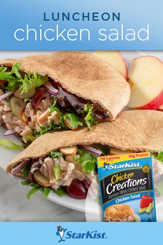 a chicken salad with lettuce and apples on a plate next to a carton of crackers