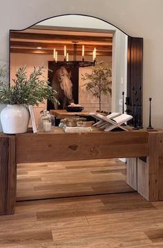 a mirror sitting on top of a wooden table next to a vase filled with flowers