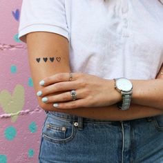 a woman with tattoos on her arm standing in front of a wall