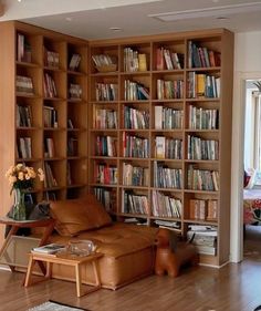 a living room filled with lots of books on top of a wooden book shelf next to a window