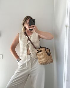 a woman is taking a selfie with her cell phone while holding a straw bag