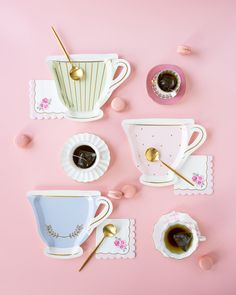 coffee cups and saucers with spoons on a pink surface