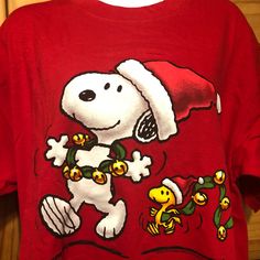 a red shirt with a snoopy christmas design on it's chest and the image of a dog wearing a santa hat